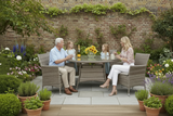 People sitting around a garden table with flowers and plants in the background