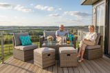 Two people sitting on a patio set with drinks and a view of a scenic landscape.