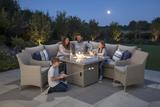 Family gathered around a fire pit table in a garden setting at night.