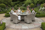 Group of people sitting around a round outdoor dining table in a garden setting.