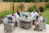 Family sitting outdoors on patio furniture with a wooden fence and garden in the background