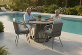 Two elderly people sitting at a round outdoor table by a pool