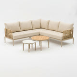 Beige sectional sofa with rattan frames and wooden tables on a white background