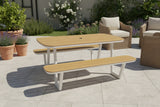 Outdoor patio set with wooden table and benches on a tiled patio.