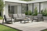 Outdoor patio set with white cushions on a wooden deck, surrounded by plants.