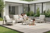 Family sitting on outdoor furniture with a child playing on a patio