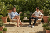 Two people sitting on chairs in a garden setting with plants around.