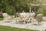 Two people sitting on a patio set with a table and chairs in a garden setting.